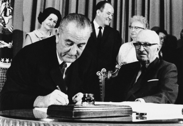 President Lyndon Johnson signs the Medicare Bill into law while former President Harry S. Truman, right, observes during a ceremony at the Truman Library in Independence, Mo. on July 30, 1965. Photo courtesy of Associated Press.